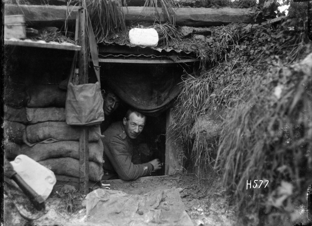 Two soldiers peer out of theirdugout at the front line, Hebuterne, France. 13 May 1918.